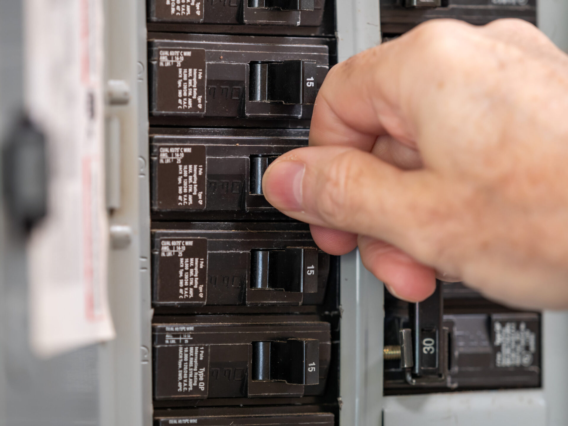 Male electrician turning off power for electrical outlet at circ