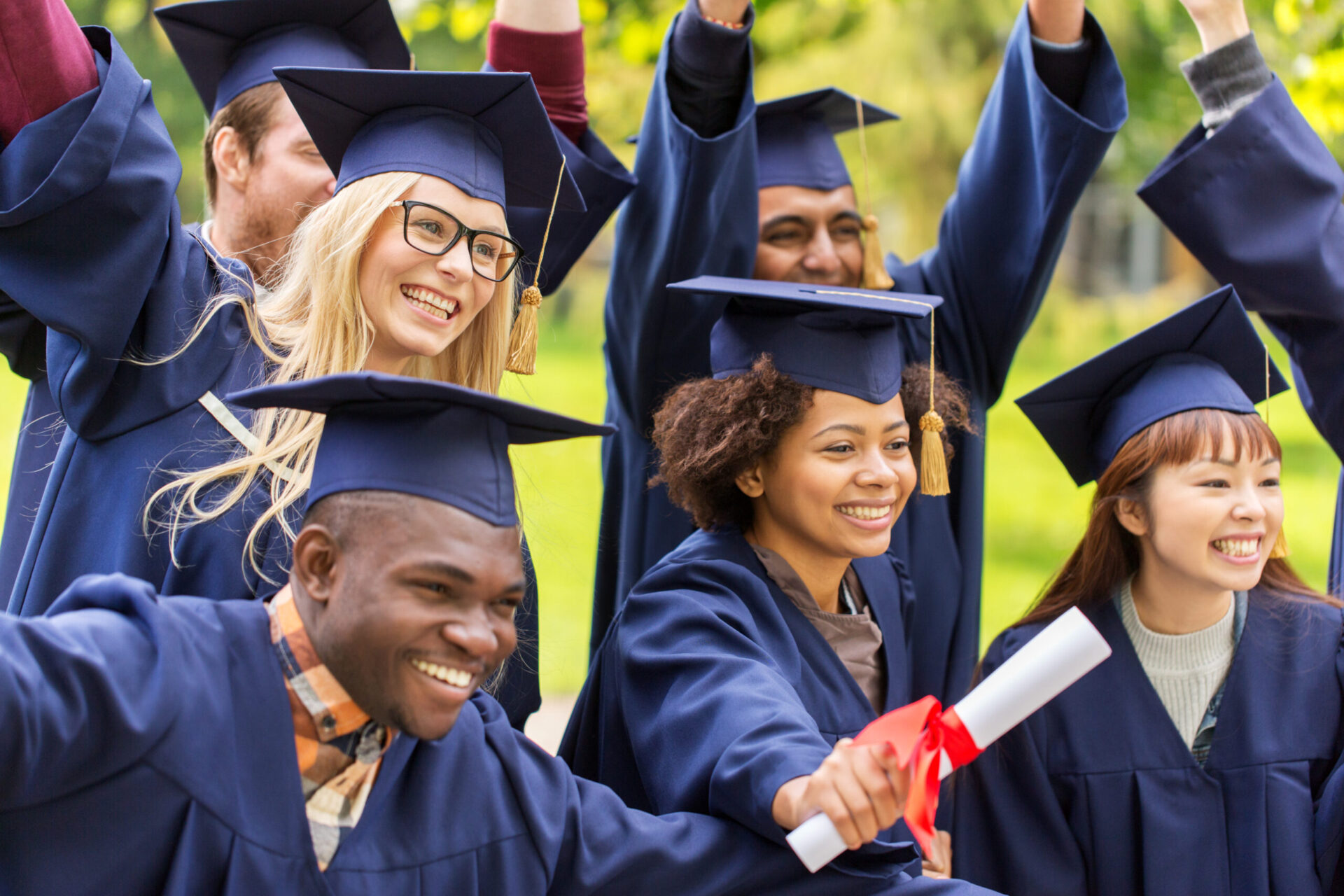 happy students in mortar boards with diplomas