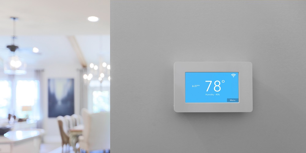 Home with smart thermostat mounted on wall with touchscreen