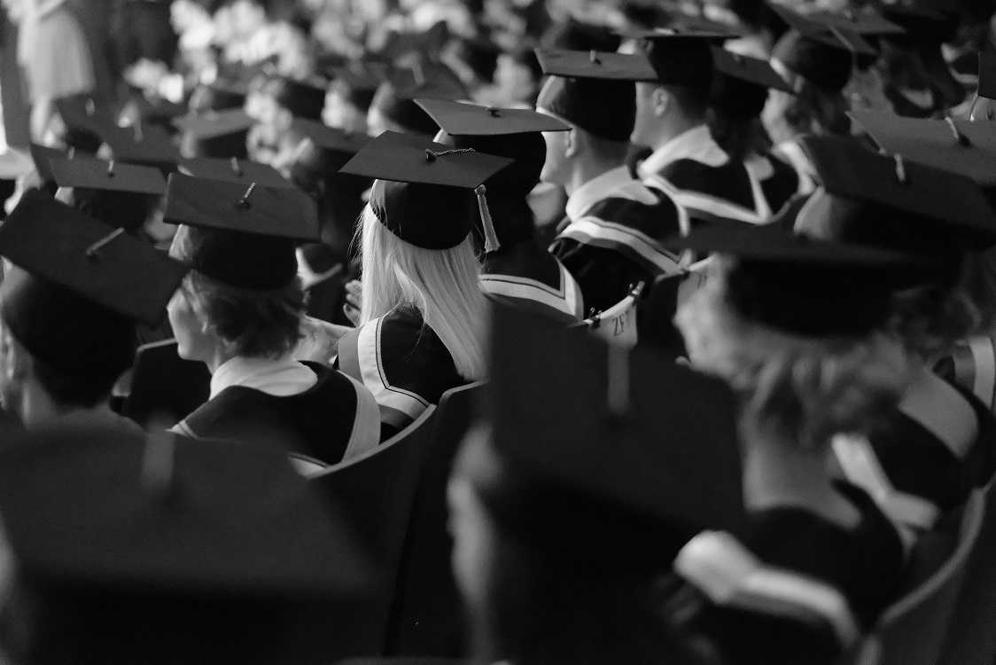 Square academic caps of graduates sitting in the university hall at the presentation of diplomas.