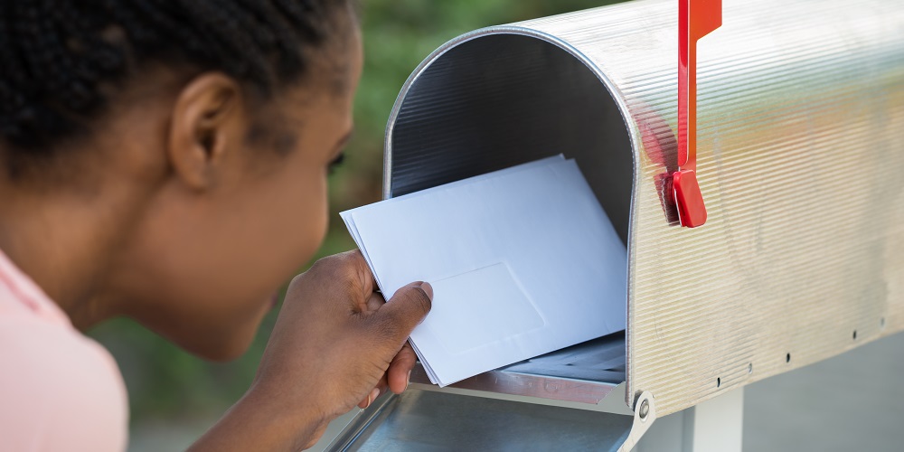 Woman Putting Letter In Mailbox