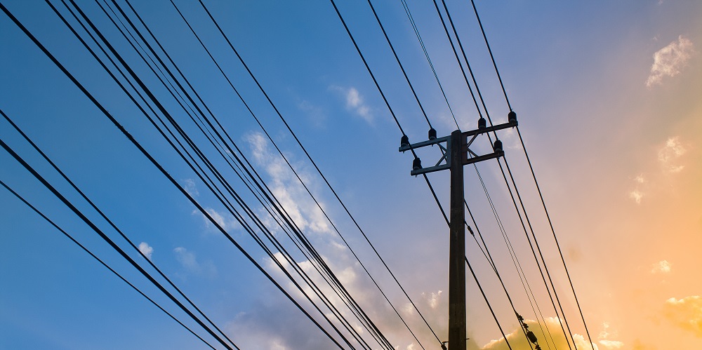 Silhouette, Electricity transmission lines and power poles Sunshine twilight sky backdrop.